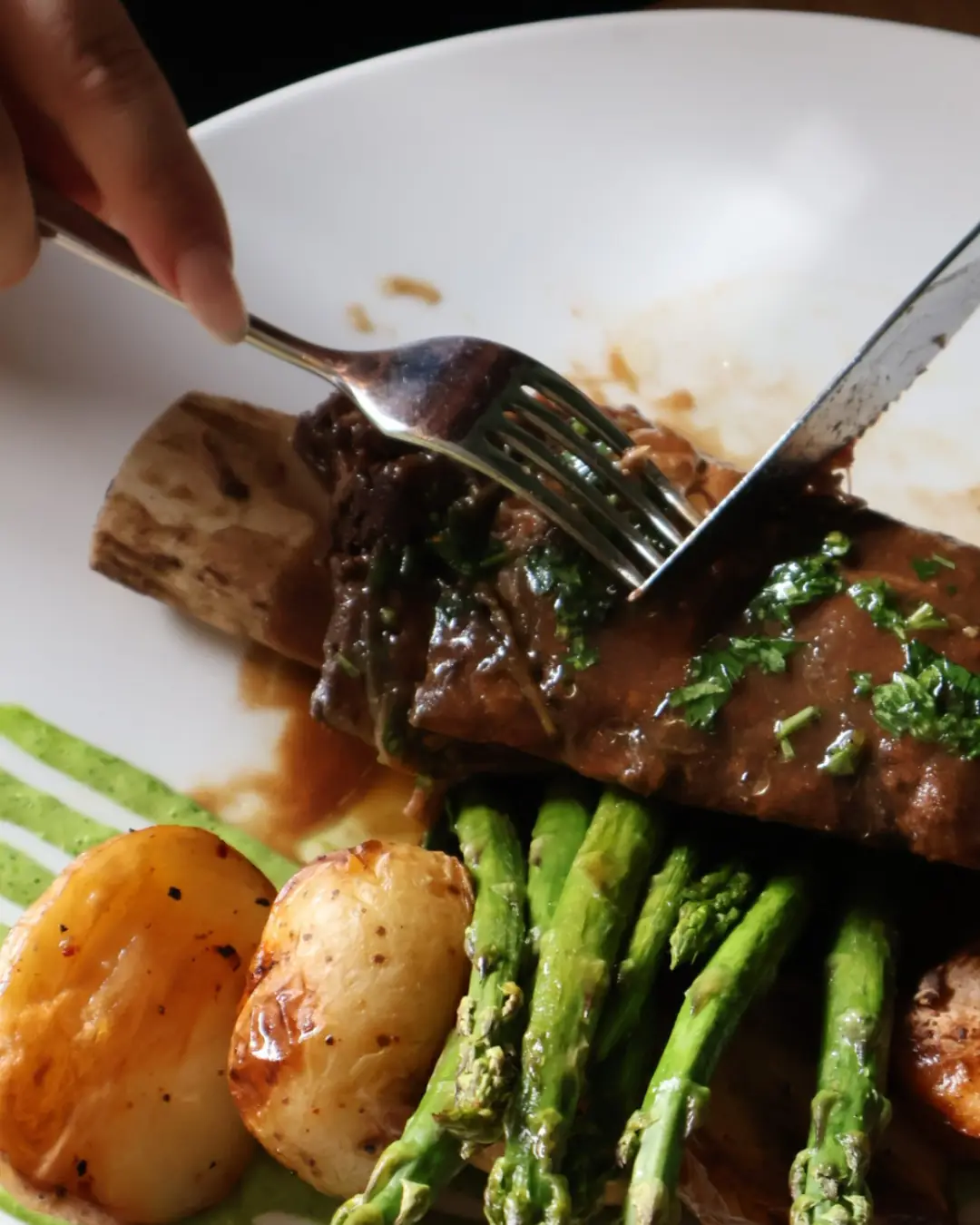 Côte courte de bœuf braisée avec pommes de terre et asperges, servie au restaurant SAUCE