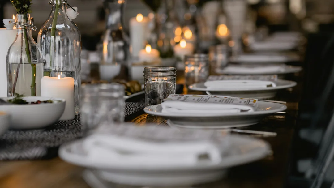 Longue table dressée, bougies et assiettes blanches