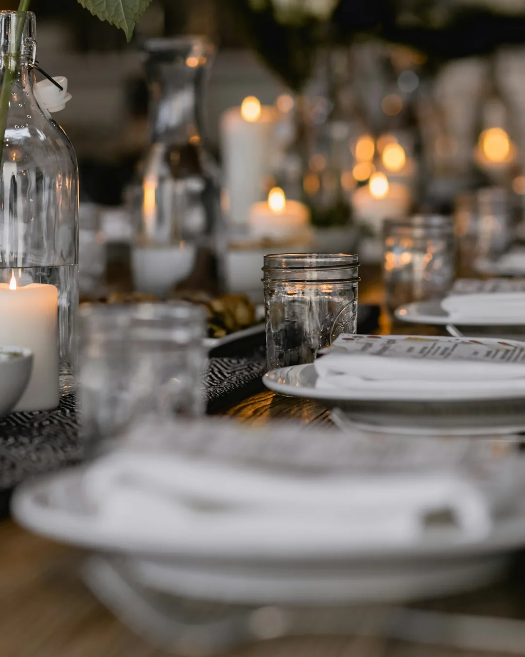Longue table dressée, bougies et assiettes blanches